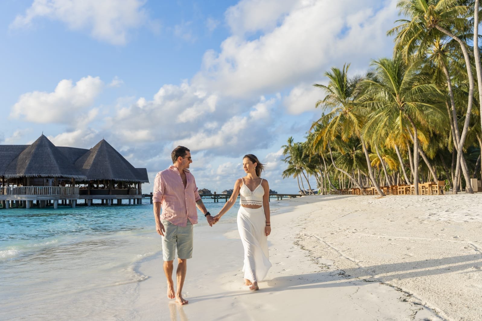 Juliana e o marido caminhando na praia nas Maldivas