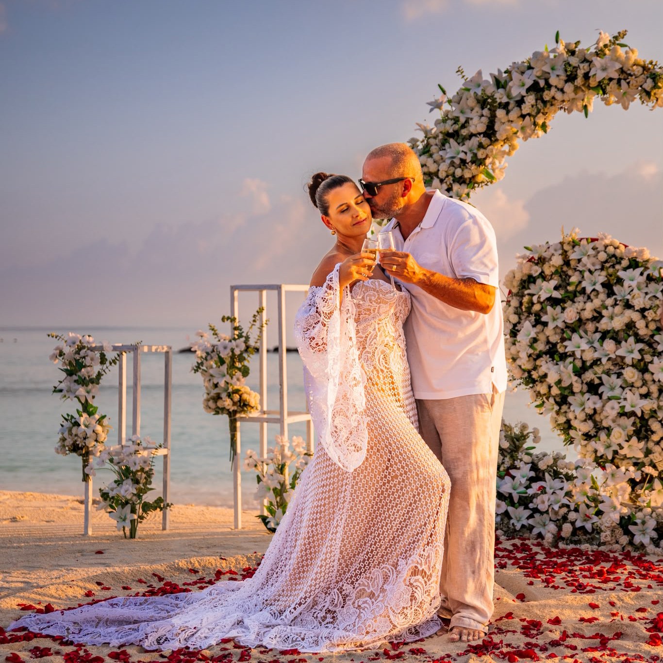Nicolle e o marido brindando ao pôr do sol nas Maldivas